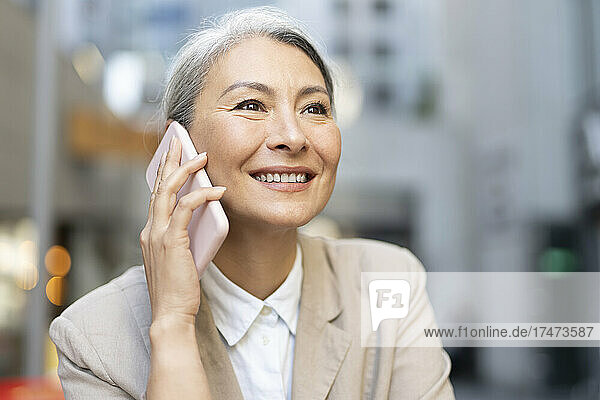 Happy woman with gray hair talking on smart phone