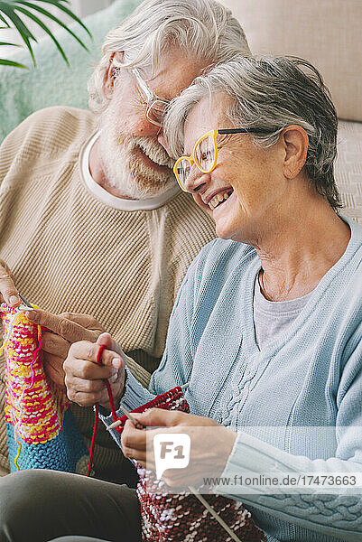 Happy senior couple with knitting needle in living room