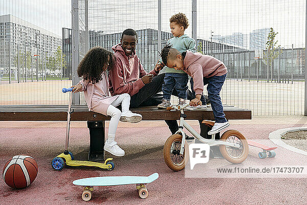 Smiling father sitting with playful children on bench