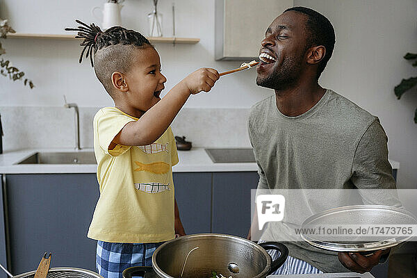 Junge füttert Vater in Küche mit Spaghetti