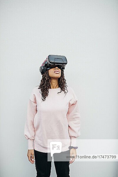 Frau benutzt Virtual-Reality-Headset vor weißer Wand