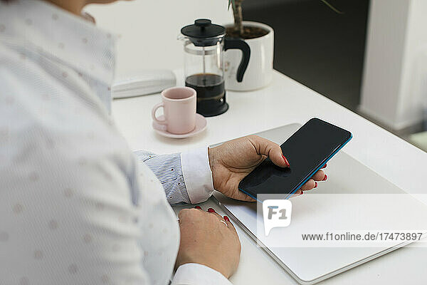 Freelancer using smart phone while working at home office
