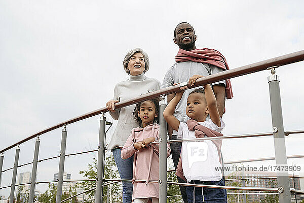 Father and grandmother standing with children at railing