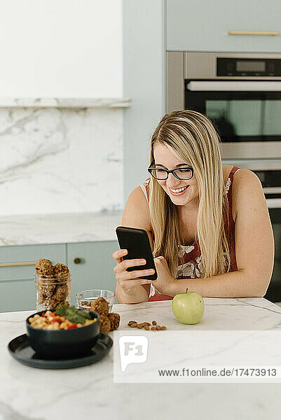Female nutrient expert photographing food through mobile phone in kitchen