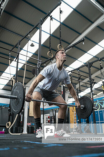 Young male athlete lifting weights while exercising in gym