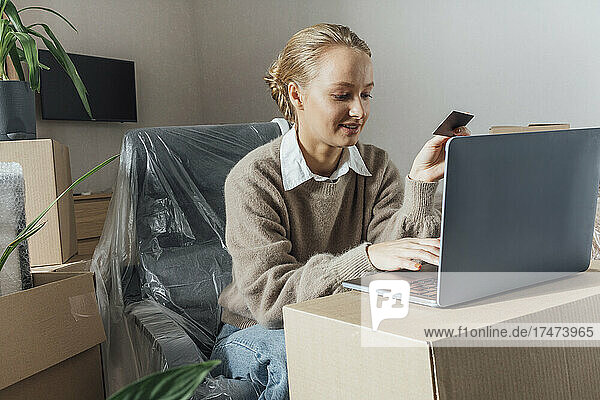 Young woman doing online shopping through credit card on laptop at home