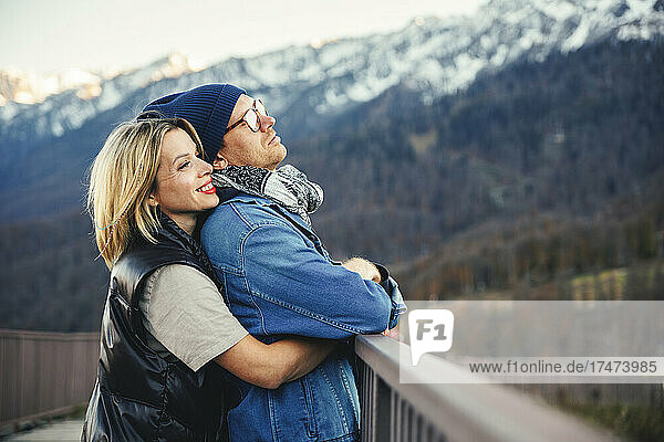 Smiling woman hugging man on bridge