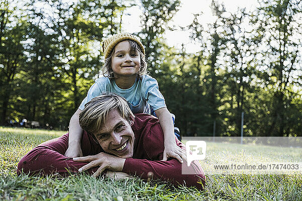 Father and son lying on grass in park