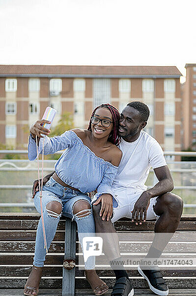 Lächelndes junges Paar macht Selfie auf Bank