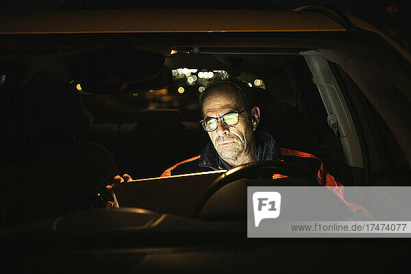 Engineer wearing eyeglasses using laptop in car