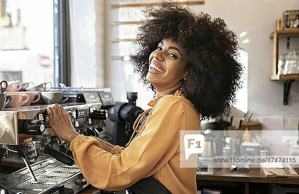 Waitress with afro hairstyle at coffee machine in cafe