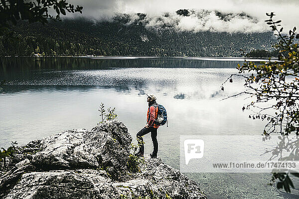 Male backpacker looking at lake in forest