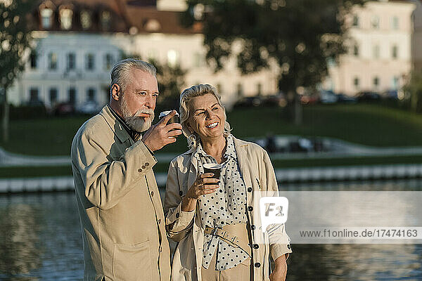 Couple having coffee at embankment during sunset