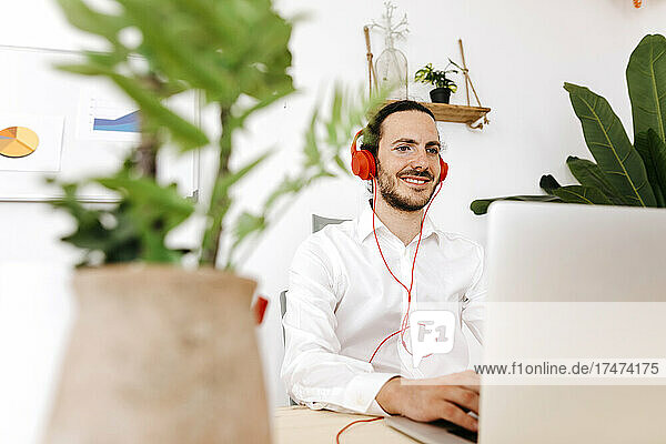 Geschäftsmann mit Kopfhörern und Laptop im Kreativbüro