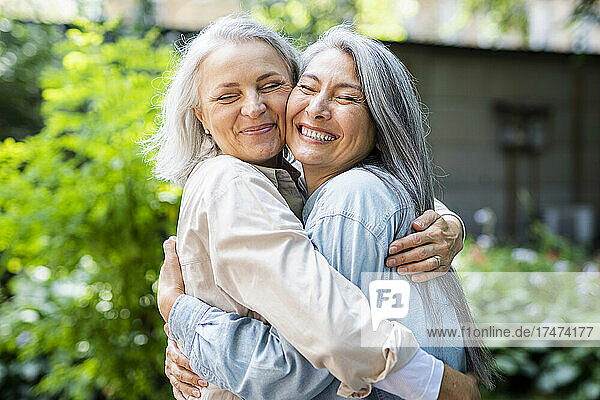 Happy women with eyes closed embracing each other
