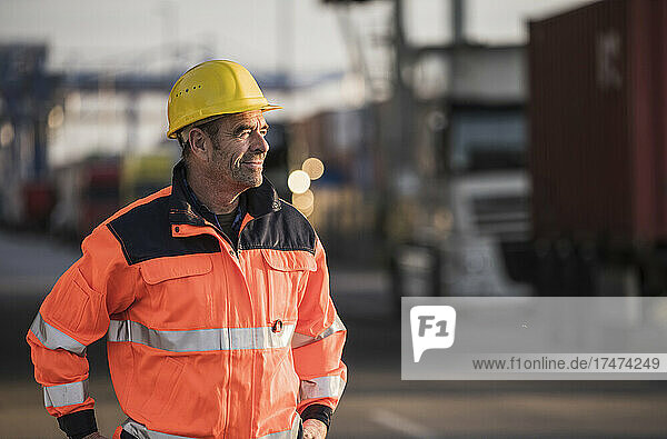 Smiling male worker with reflective jacket at industry