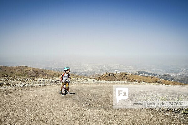 Kleiner Junge fährt auf seinem ersten Fahrrad bergauf in den Bergen der Sierra Nevada  Andalusien  Spanien  Europa