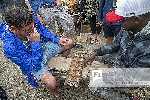 Holidaymaker playing Oril (board game with two times six wells and 48 pieces) with local  Espargos  Ilha do Sal  Cabo Verde