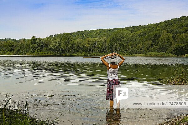 Frau mit Sonnenhut und Rock steht im Wasser  Pfuhler See  Badegewässer  Neu-Ulm  Bayern  Deutschland  Europa