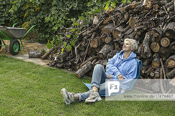 Gelassene Frau ruht sich am Holzstapel im Hinterhof aus