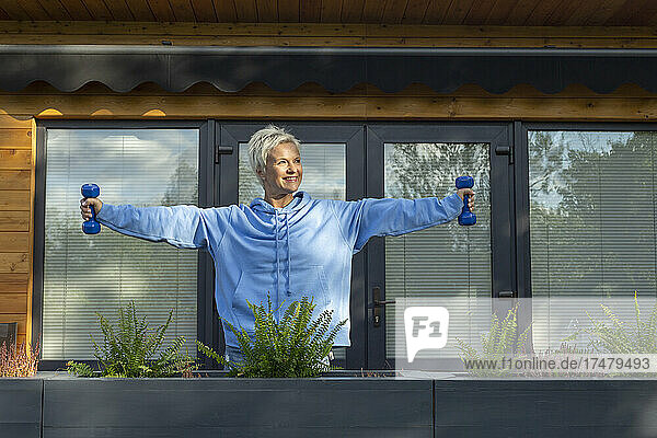 Glückliche Frau beim Training mit Hanteln auf der Terrasse