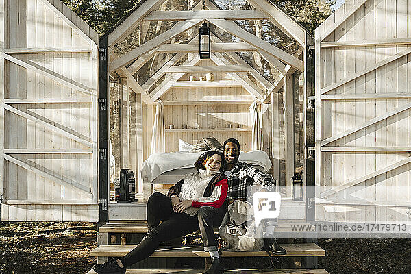 Porträt eines lächelnden Paares  das auf den Stufen einer Hütte sitzt