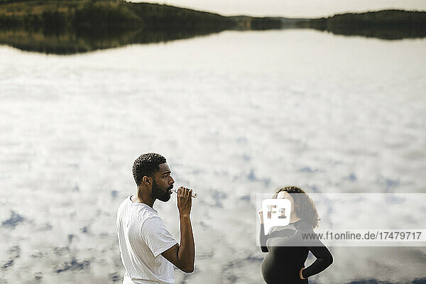 Junge schwangere Frau beim Zähneputzen mit ihrem Freund am Morgen am See