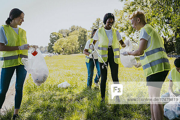 Lächelnde männliche und weibliche Freiwillige beim Reinigen von Kunststoffen