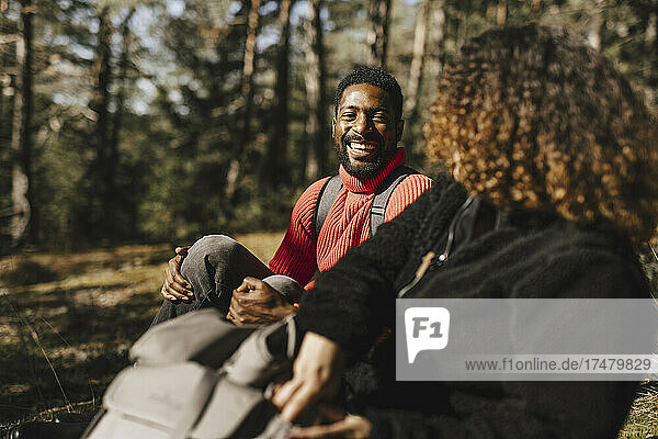 Happy man talking with girlfriend in forest during vacation