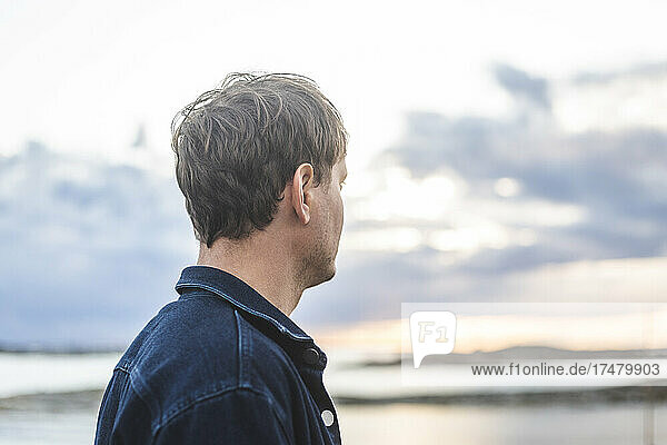 Side view of mid adult man looking at view during sunset