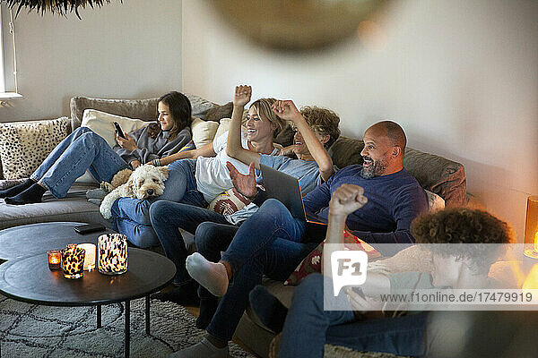 Family cheering while watching TV together in living room at home