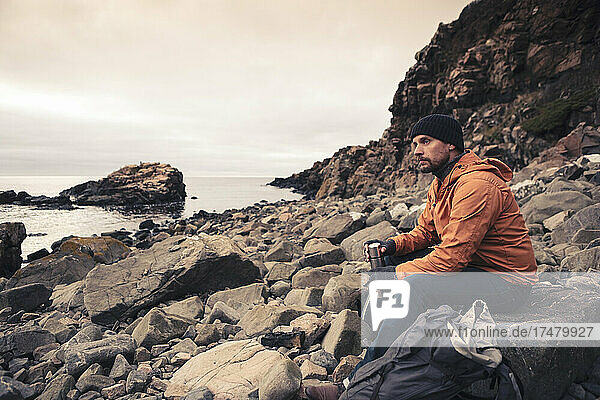 Nachdenklicher Mann sitzt auf einem Felsen am Strand