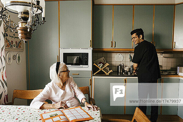 Ältere Frau im Gespräch mit männlichem Pflegepersonal bei der Arbeit in der Küche