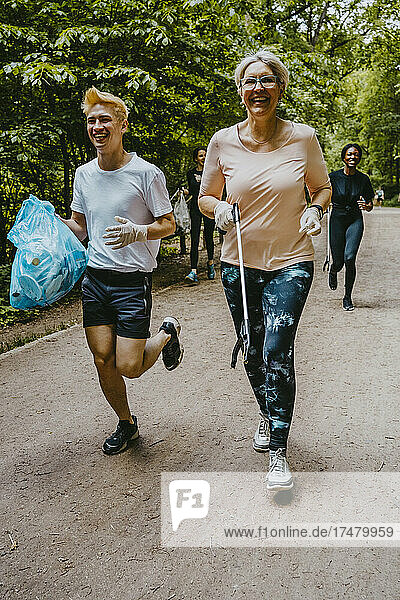 Cheerful female and male plogging with plastic bag in park