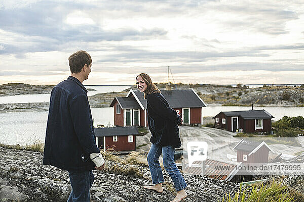 Lächelnde Freundin spielt mit ihrem Freund auf einer Insel bei Sonnenuntergang