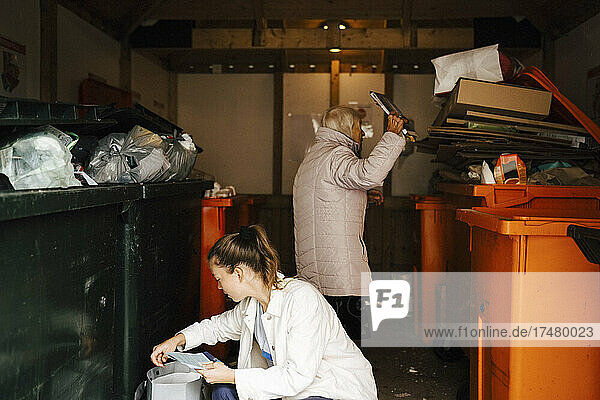 Female caregiver and senior woman with wastes in storage room