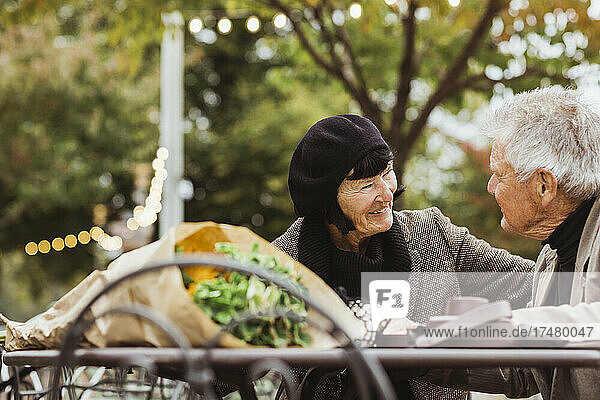 Lächelnde ältere Frau  die einen Mann im Park im Urlaub betrachtet