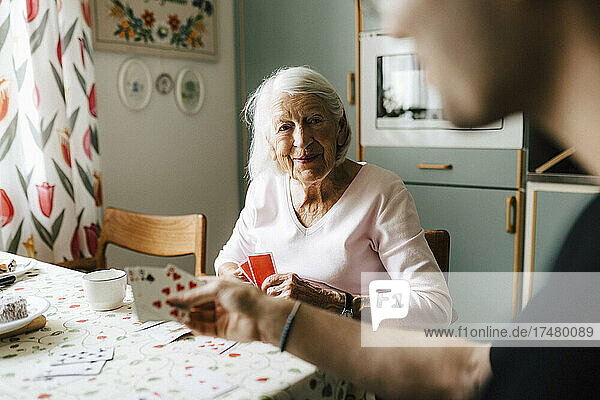 Ältere Frau spielt Karten mit Pfleger am Esstisch