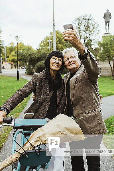 Älteres Paar  das am Wochenende im Park ein Selfie mit einem Elektrofahrrad per Smartphone macht