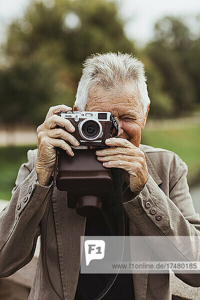Älterer Mann beim Fotografieren mit Kamera am Wochenende