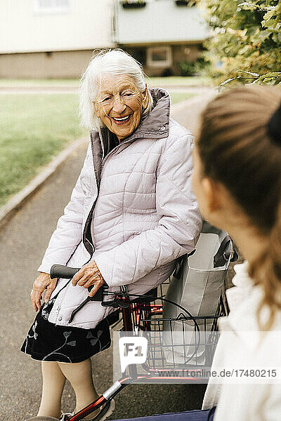 Glückliche ältere Frau im Gespräch mit einer Betreuerin im Vorgarten