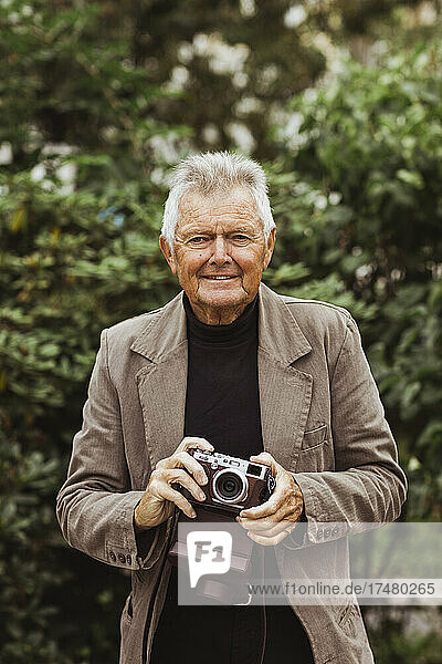 Porträt eines älteren Mannes mit Kamera im Park
