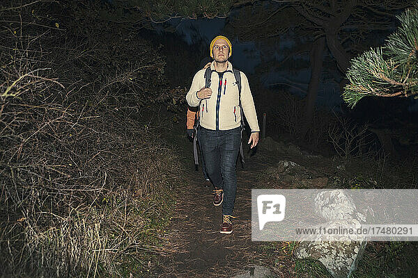 Mature man hiking in forest at night during vacation