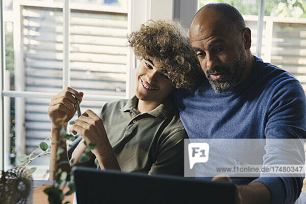 Vater hilft seinem Sohn bei den Hausaufgaben am Laptop zu Hause