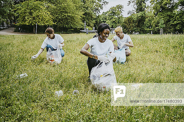 Lächelnde männliche und weibliche Freiwillige  die Plastik im Park aufsammeln