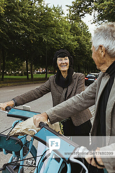 Lächelndes Seniorenpaar mit Elektrofahrrädern auf der Straße