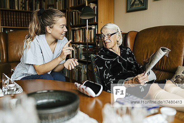Lächelnde Betreuerin im Gespräch mit einer älteren Frau im Wohnzimmer