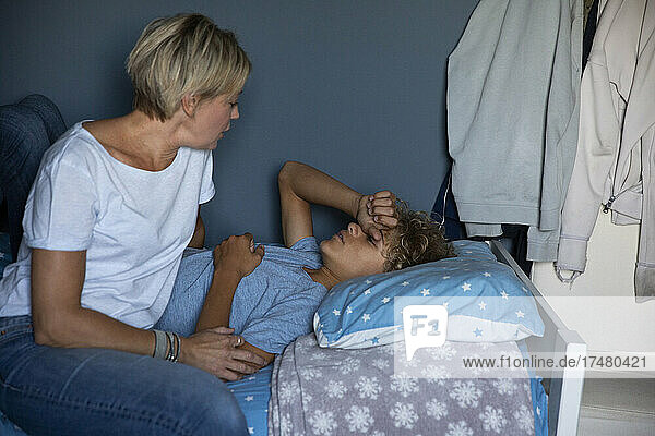Blonde Frau im Gespräch mit ihrem Sohn  der zu Hause auf dem Bett liegt