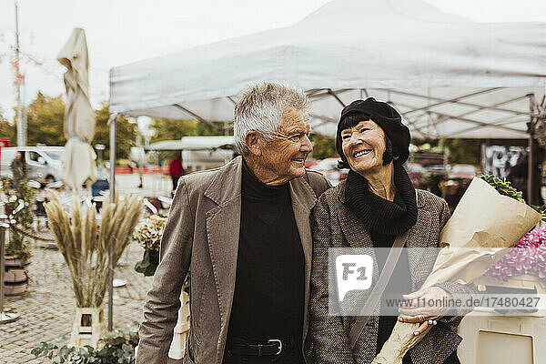 Cheerful senior couple walking in market during vacation