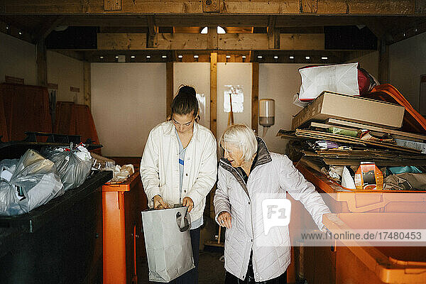 Ältere Frau und Mitarbeiterin des Gesundheitswesens  die im Lagerraum in eine Tasche schauen